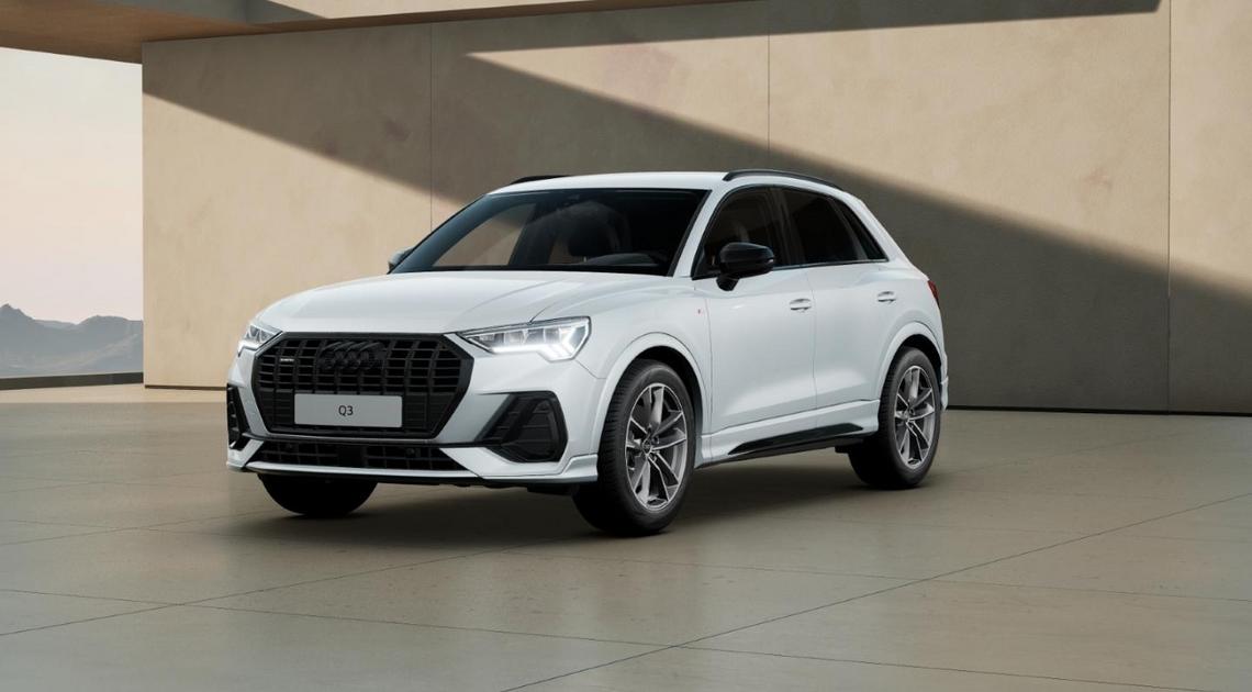 Front Links Ansicht eines weißen Audi Q3 vor beiger, moderner Architektur.