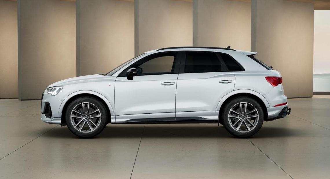 Seitenansicht eines weißen Audi Q3 vor moderner, beiger Architektur
