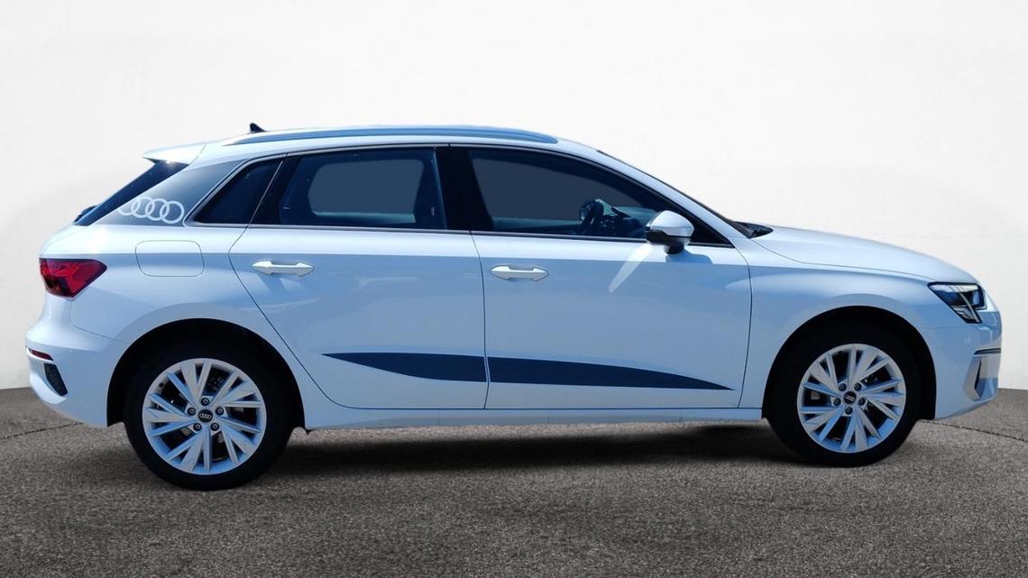 Seitenansicht weißer Audi A3 Sportback mit schwarzen Dekor-Akzenten vor grauem Hintergrund